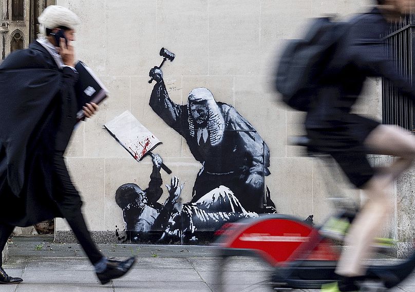 New artwork by Banksy which portrays a judge beating a protester with a gavel at the Royal Courts of Justice in London